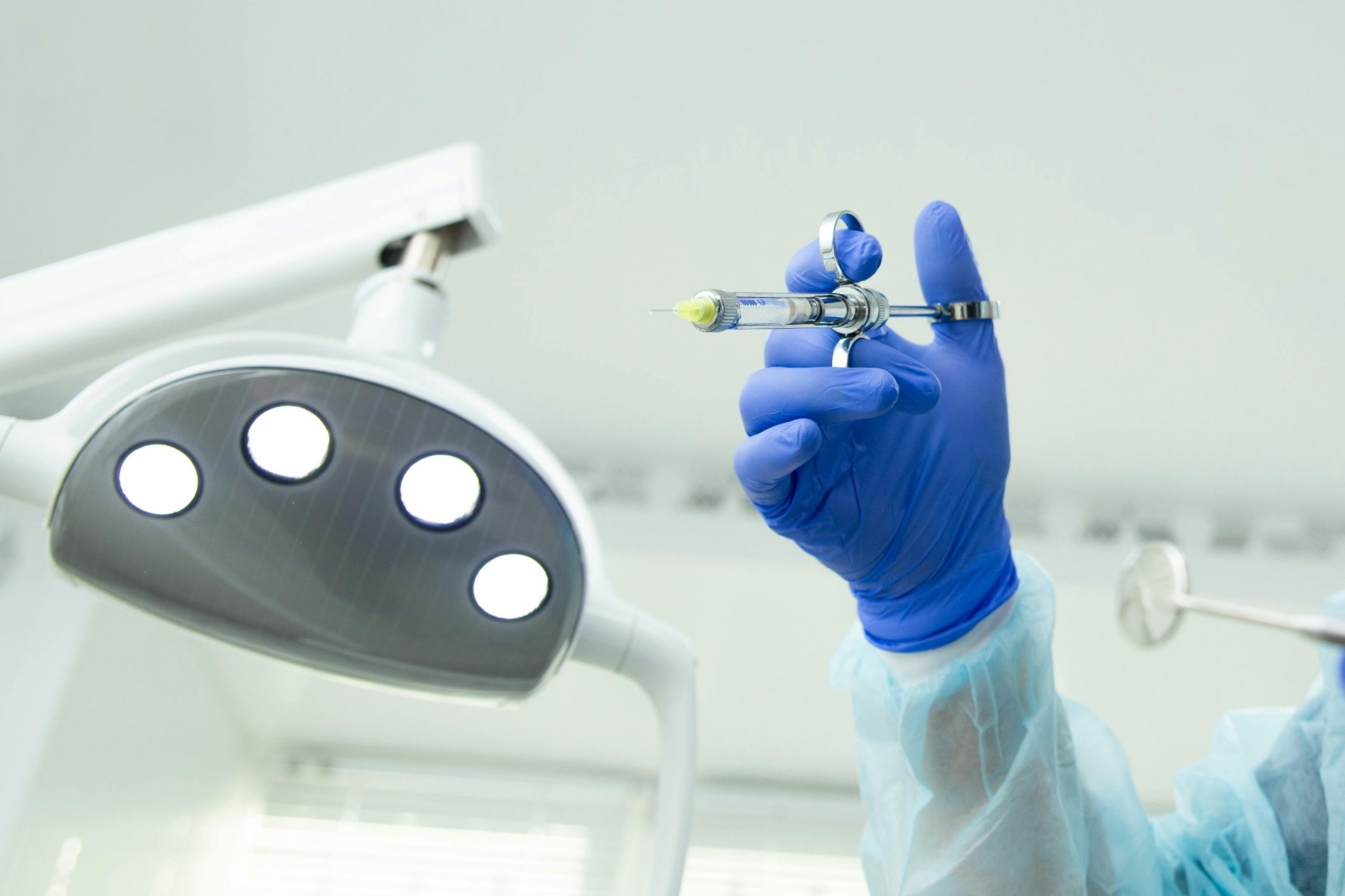 close-up of a gloved hand holding a dental anesthetic syringe