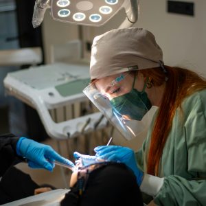 female dentist in surgical gloves and a mask performing a bone graft