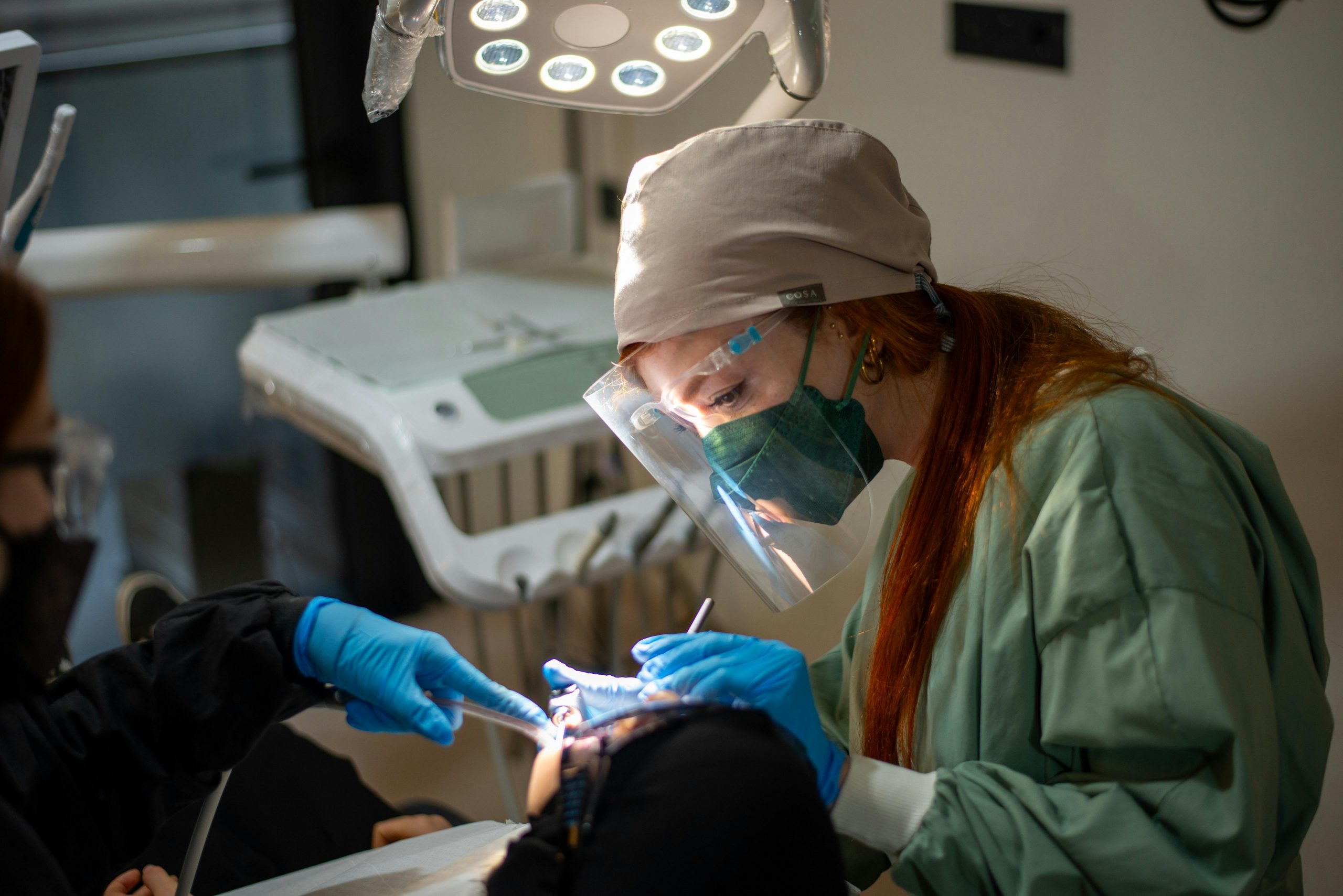 female dentist in surgical gloves and a mask performing a bone graft