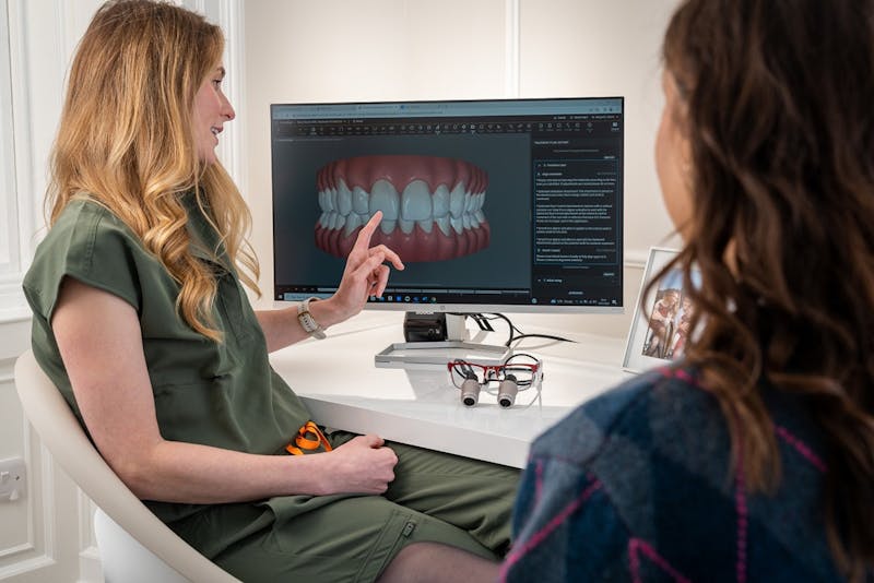 a dentist showing a patient's teeth on the screen